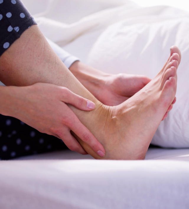 Πόνος στα πόδια από ορθοστασία: Πώς να τον αντιμετωπίσετε γυναικεία πατούσα σε καναπέ που την ακουμπά γυναικείο χέρι