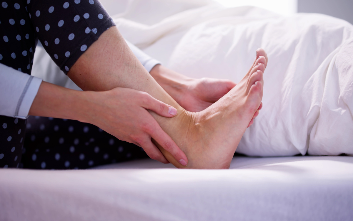 Πόνος στα πόδια από ορθοστασία: Πώς να τον αντιμετωπίσετε γυναικεία πατούσα σε καναπέ που την ακουμπά γυναικείο χέρι